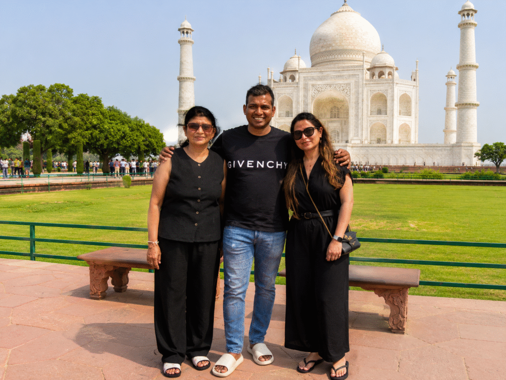 Family standing together for a photo in front of the Taj Mahal during a sunrise Taj Mahal tour