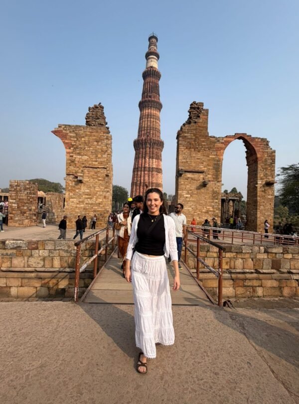 Tourist posing in front of Qutub Minar tower during a private half day delhi tour
