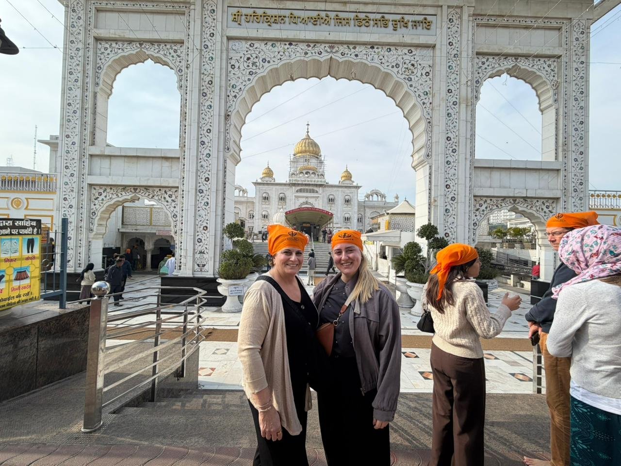 Delhi Temples and Spiritual Sites Tour visitors posing at Gurudwara Bangla Sahib during a spiritual sightseeing experience in Delhi