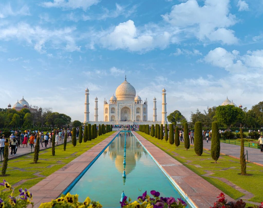 Taj Mahal in Agra with reflecting pool and manicured gardens, iconic white marble mausoleum and minarets under a clear sky – popular North India tourist attraction.