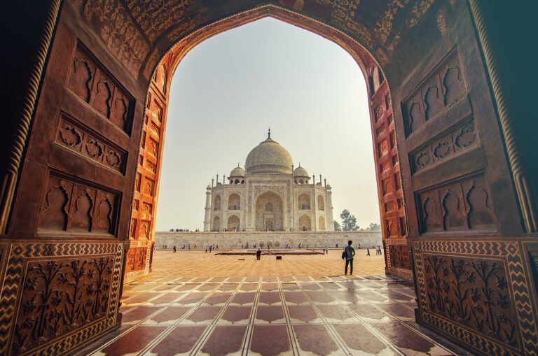 Taj Mahal framed through a red sandstone archway in Agra, India Golden Triangle tour destination, showcasing Mughal architecture and popular North India tourist attraction