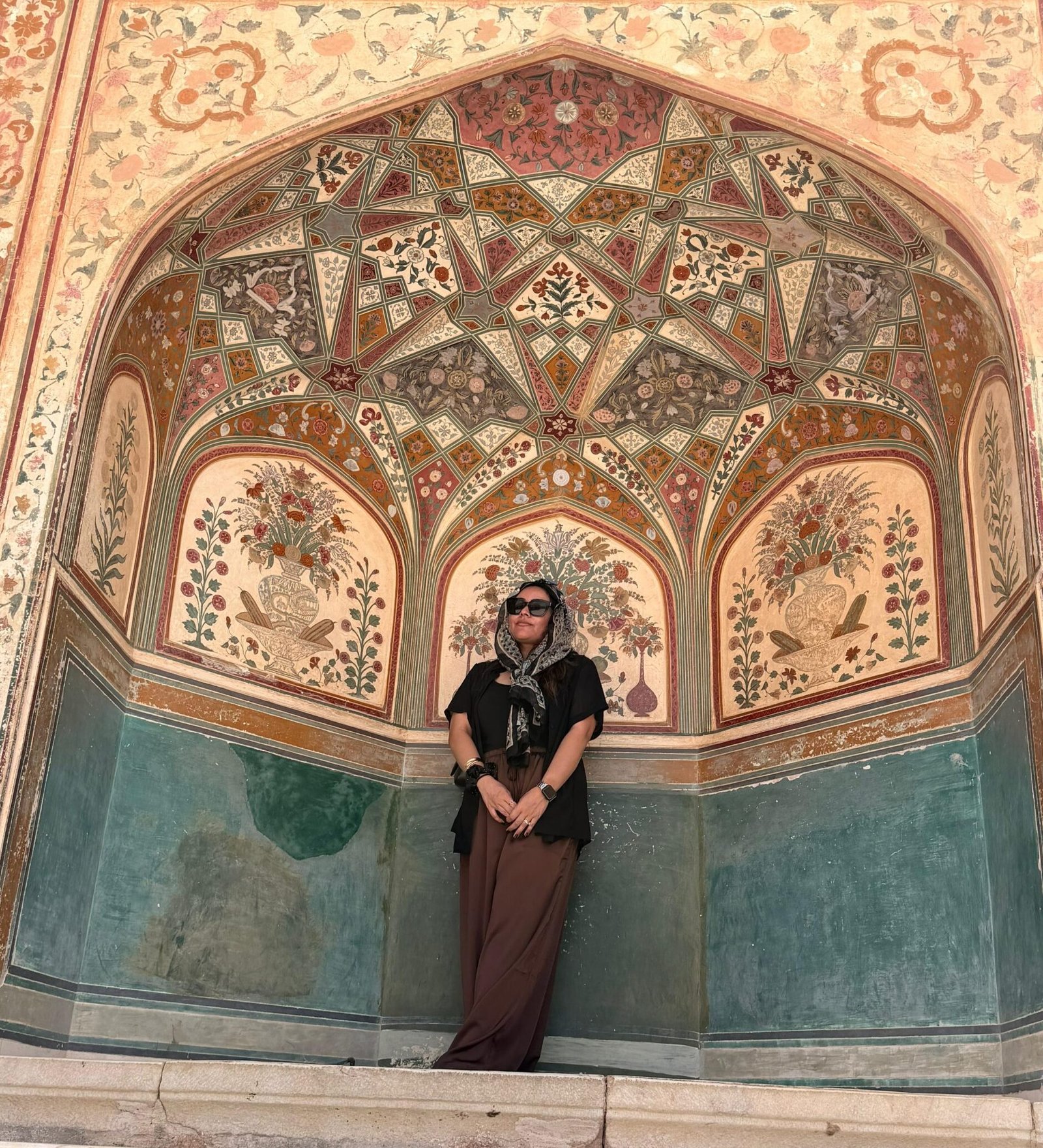 Traveler admiring the intricate floral paintings inside a historic Mughal palace in Jaipur