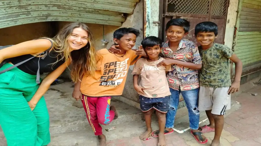 From Chandni Chowk to Dharavi, a traveler smiling with local children during a Dharavi walking tour in Mumbai.